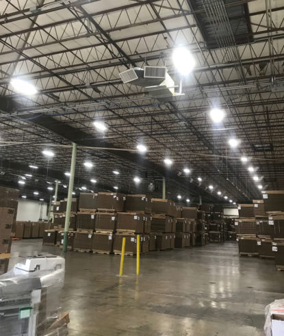 A warehouse with lots of boxes and lights, requiring electrical repair.