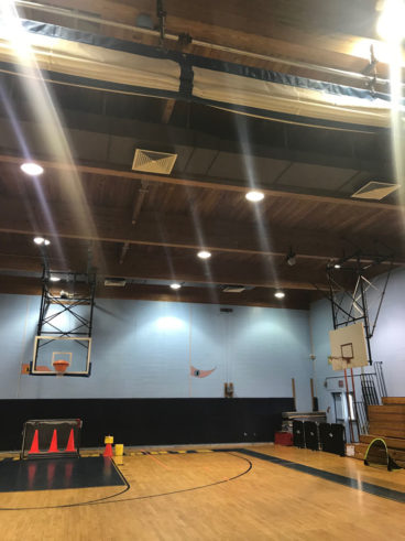 A gym with a basketball court and a basketball hoop offering sports facilities.