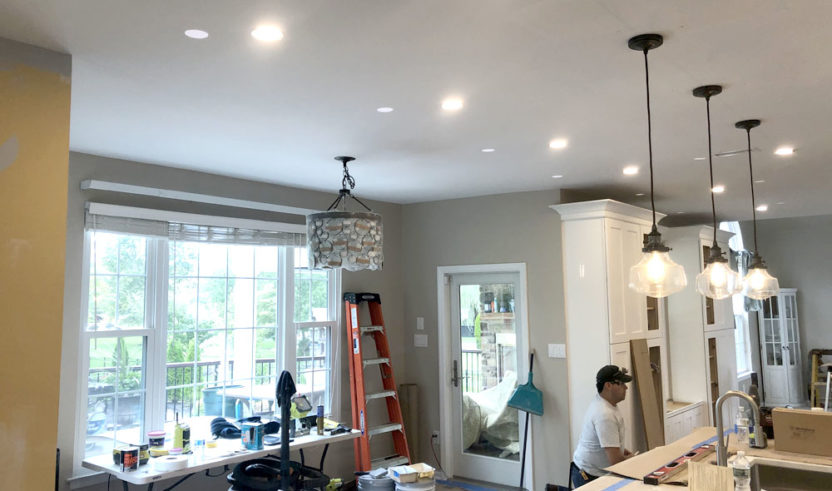 A master electrician is remodeling a kitchen with a lot of light fixtures.