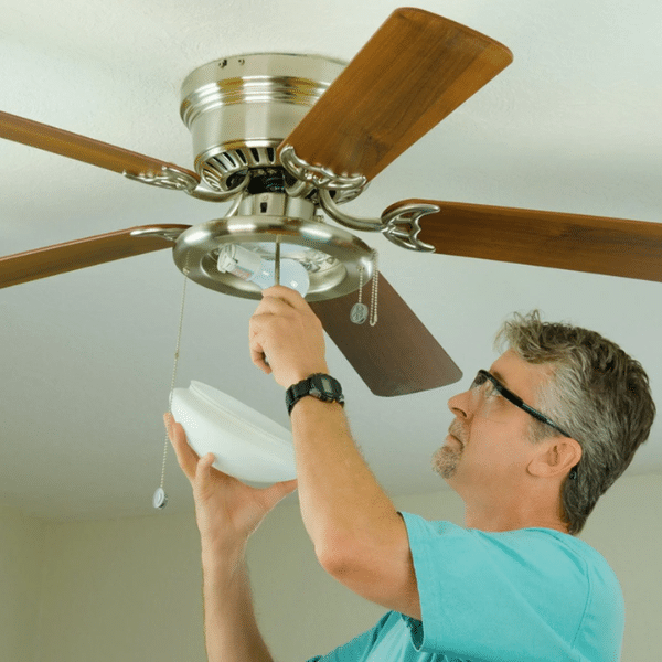 Hand adjusting the ceiling fan direction switch for winter use