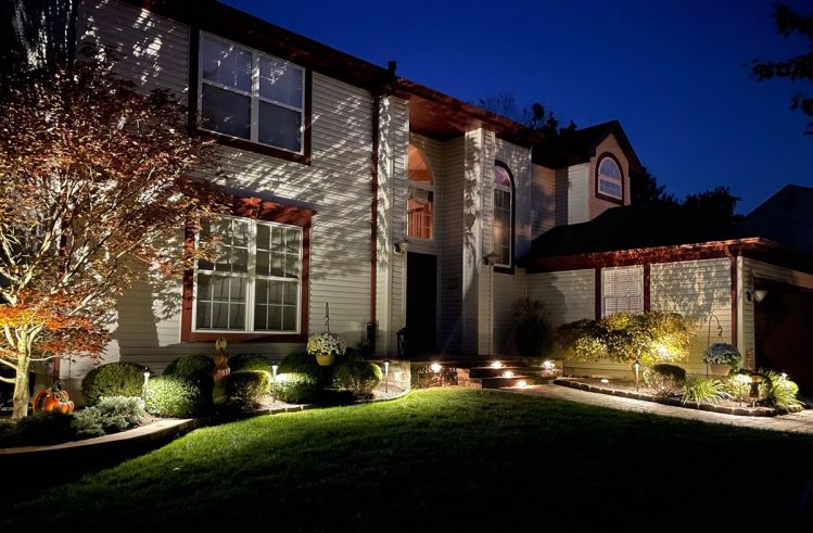 A residential electrician enhances a home's ambiance at night with landscape lighting.